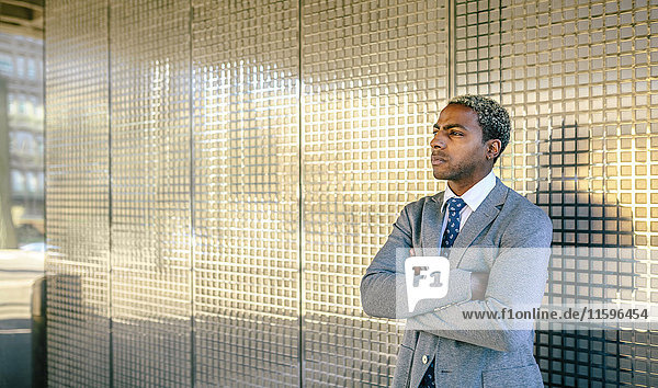 Businessman standing in front of golden wall with arms crossed