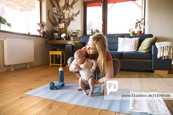 Mother with baby and dumbbells at home