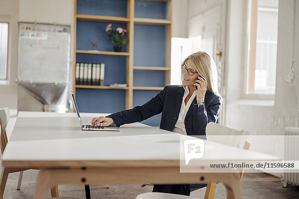 Geschäftsfrau mit Laptop und Handy im Büro