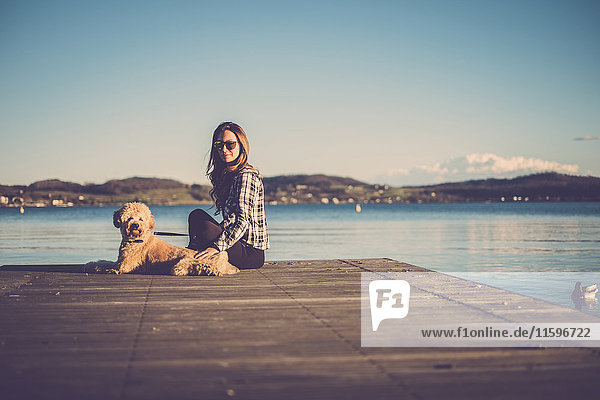 Woman sitting on jetty with her dog