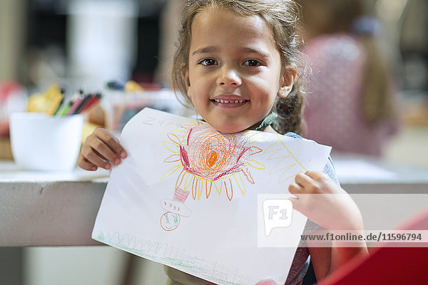 Lächelndes Mädchen zeigt Zeichnung
