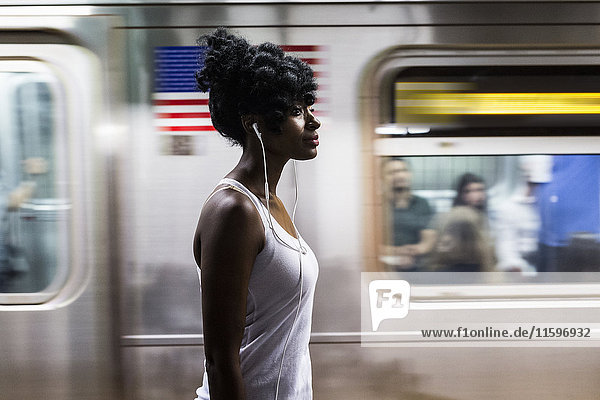 USA  New York City  Manhattan  woman with earphones on subway station platform