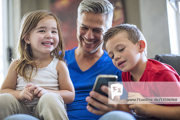 Happy father with children sharing cell phone