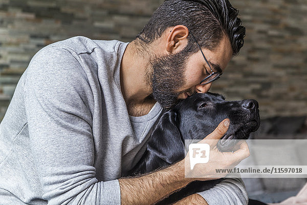 Mann kuschelt mit seinem Hund zu Hause