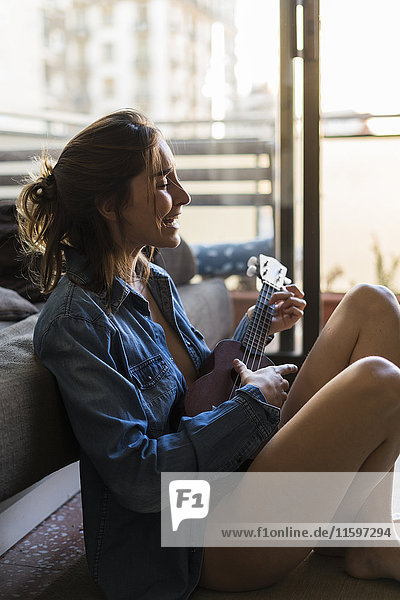 Young woman playing ukulele at home
