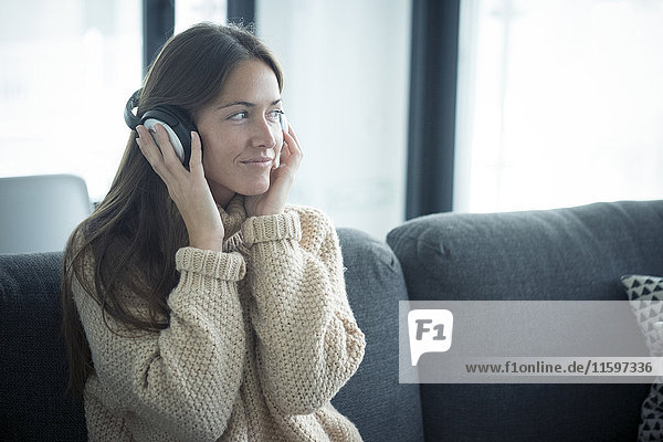 Smiling young woman listening to music at home