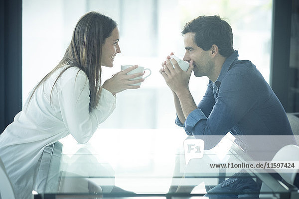 Happy young couple sitting at table with coffee cups
