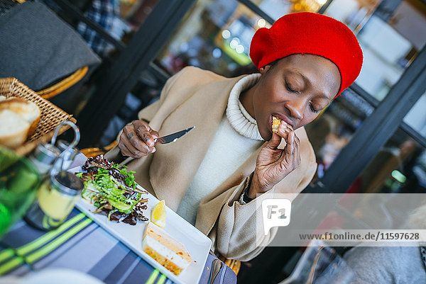 Junge Frau in Paris beim Essen im Bistro