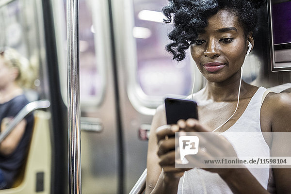 Portrait of woman looking at cell phone in underground train