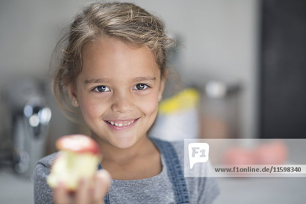 Portrait of smiling girl with apple in kitchen
