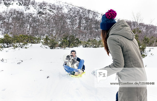 Mann und Frau haben Spaß mit Schlitten und Hund im Schnee