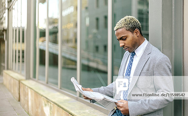 Geschäftsmann an die Wand gelehnt  Zeitung lesen