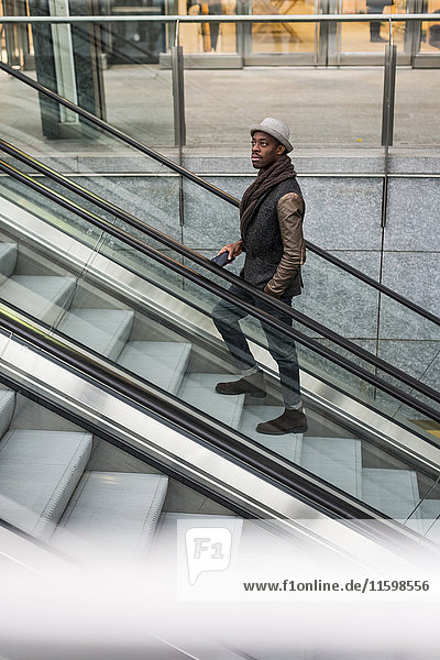 Young man standing on escalator