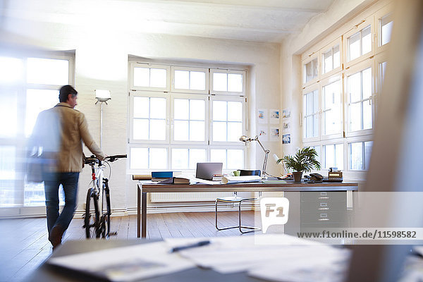 Mann mit Fahrrad in einem modernen informellen Büro