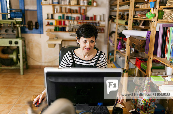 Shoemaker using computer in her workshop