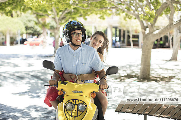Glückliches junges Paar mit Einkaufstaschen auf dem Motorroller