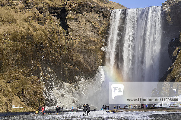 Iceland  people at Skogafoss waterfall with rainbow in winter