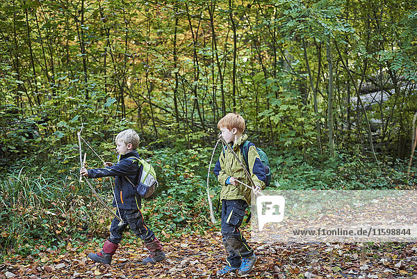 Two little boys with self-made bows and arrows in autumn