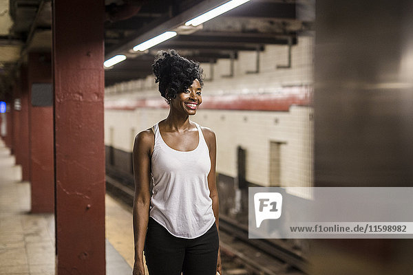 USA  New York City  Manhattan  smiling woman waiting at subway station platform