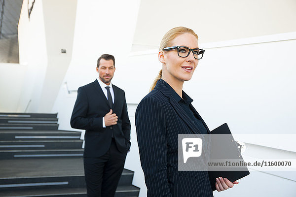 Confident businesswoman and businessman outside office building