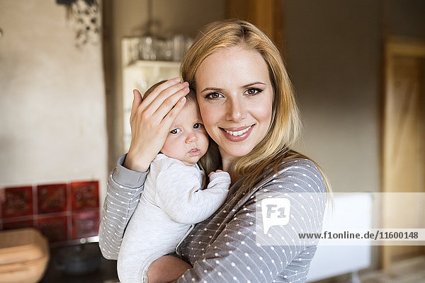 Portrait of smiling mother holding baby at home