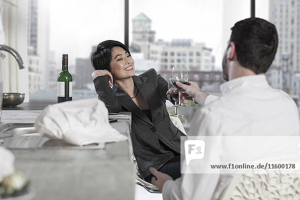 Couple raising a toast in open plan apartment with city view