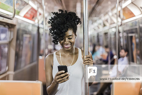 USA  New York City  Manhattan  portrait of happy woman looking at cell phone in underground train