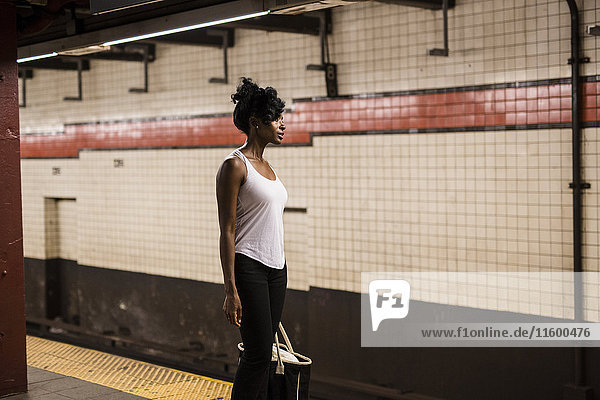 USA  New York City  Manhattan  woman with shopping bag waiting at subway station platform
