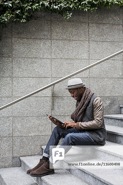 Man sitting on staircase using tablet