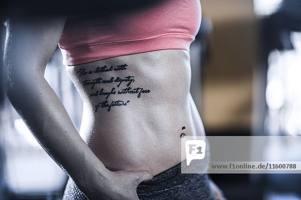 Sportliche Frau mit starken Bauchmuskeln und Tattoo