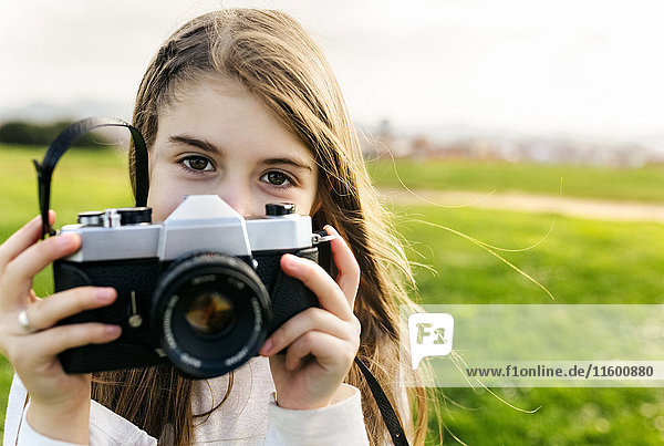 Portrait of a girl holding an old-fashioned camera outdoors