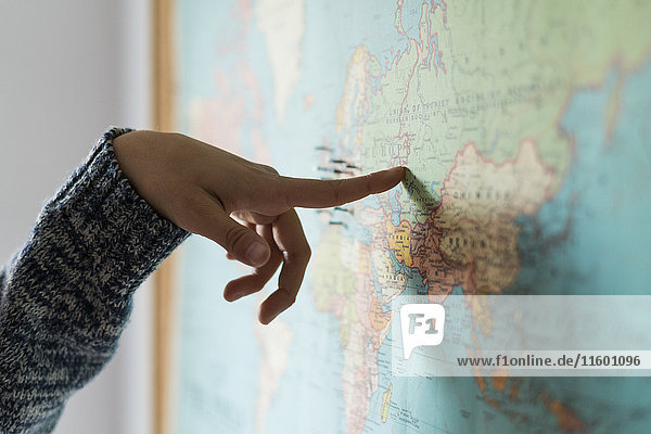 Die Hand der Frau zeigt auf die Weltkarte