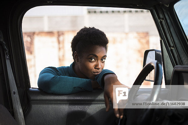 Afroamerikanische Frau lehnt sich an ein Autofenster