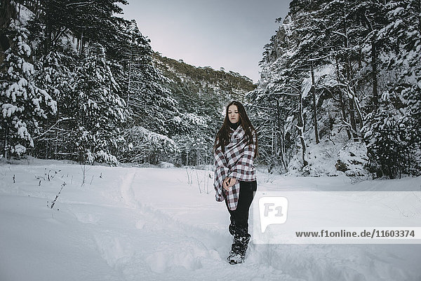 Kaukasische Frau in Decke eingewickelt im verschneiten Wald