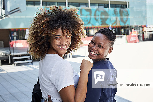 Porträt von lächelnden schwarzen Frauen  die sich in der Stadt umarmen