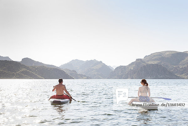 Couple sitting on paddleboards in river