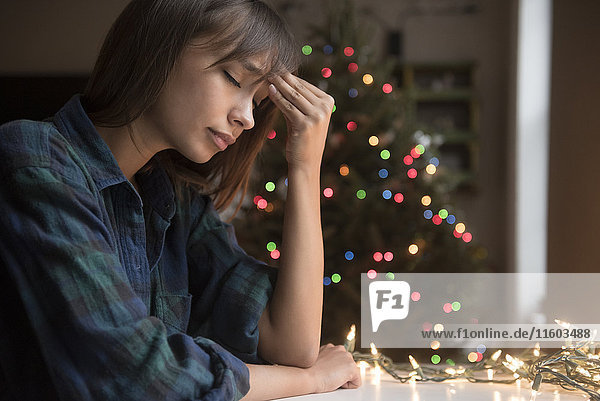 Gemischtrassige Frau mit Kopfschmerzen in der Nähe des Weihnachtsbaums