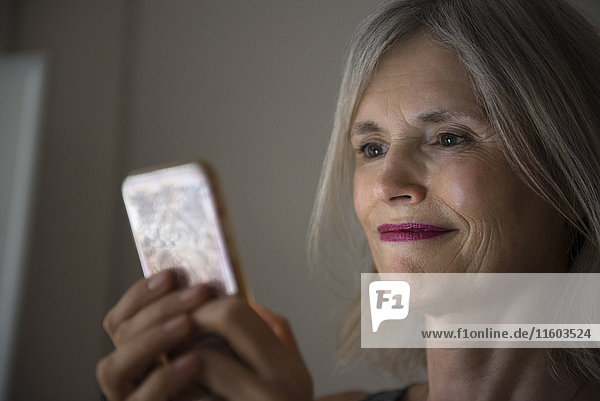 Lächelnde kaukasische Frau  die eine SMS auf ihrem Mobiltelefon schreibt