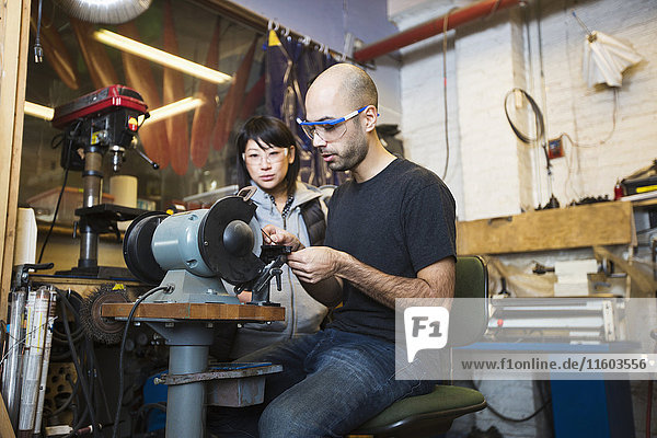 Man and woman using machinery in workshop