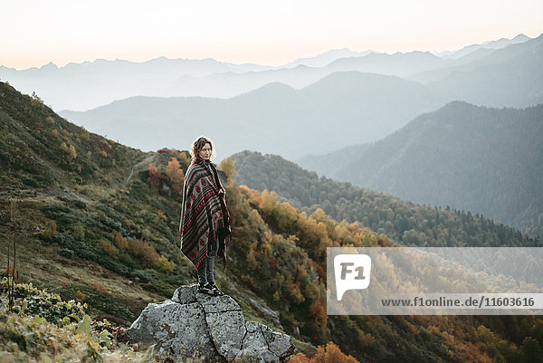 Caucasian woman standing on mountain rock overlooking valley