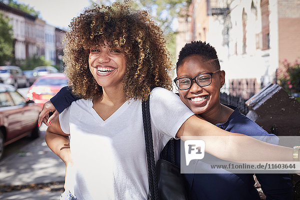 Porträt von schwarzen Frauen  die sich auf dem Bürgersteig umarmen