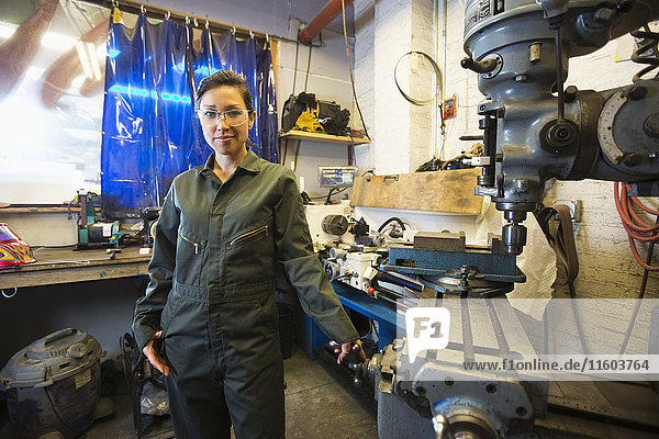 Mixed Race woman posing near machinery in workshop