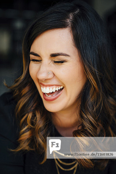 Porträt einer lachenden gemischtrassigen Frau mit gepiercter Nase