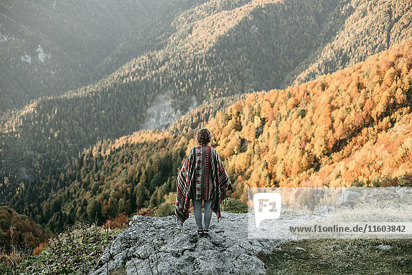 Kaukasische Frau steht auf einem Berg mit Blick auf ein Tal