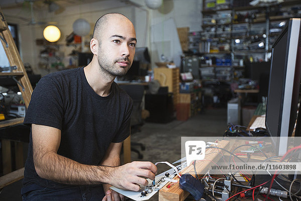 Gemischtrassiger Mann arbeitet mit Elektronik in einer Werkstatt