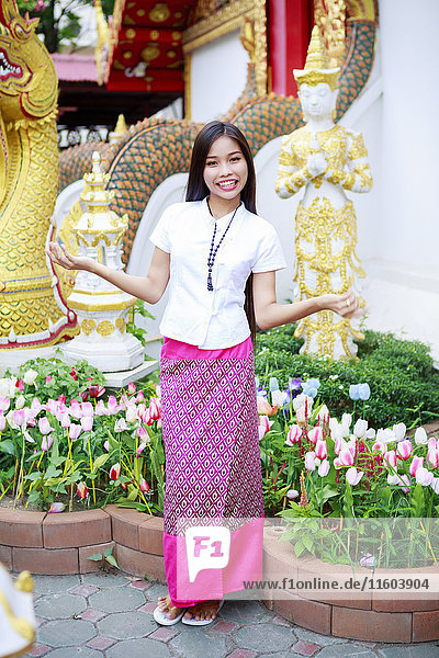 Smiling Asian woman standing in ornate garden