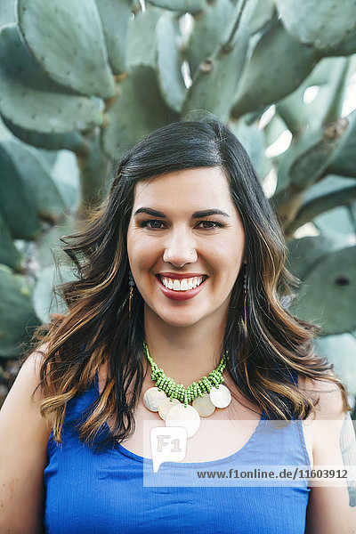Porträt einer lächelnden gemischtrassigen Frau in der Nähe eines Kaktus