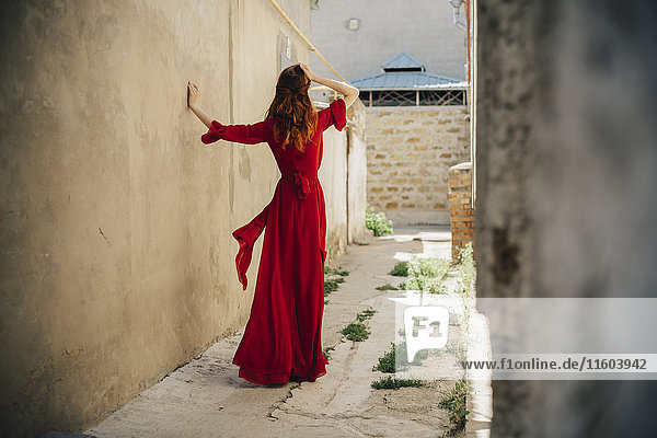 Caucasian woman wearing red dress in alley