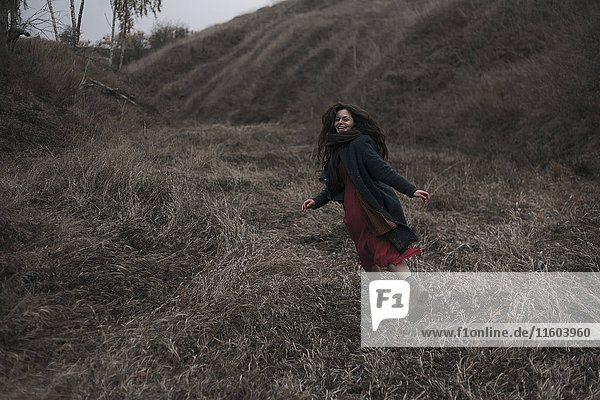 Kaukasische Frau läuft auf grasbewachsenem Hügel