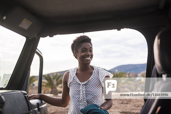 Lächelnde afroamerikanische Frau öffnet Autotür